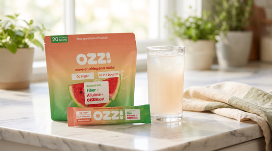 Ozzi watermelon stick pack pouch and a single stick beside a glass of the prepared drink on a sunlit marble kitchen counter.