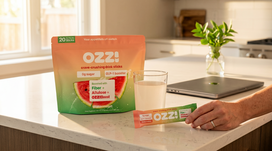 Woman holding an Ozzi stick pack in a sunlit modern kitchen, morning routine for cravings control