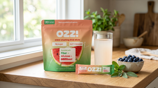 Ozzi watermelon pouch and stick beside a glass of the prepared cloudy off-white drink on a bright kitchen counter